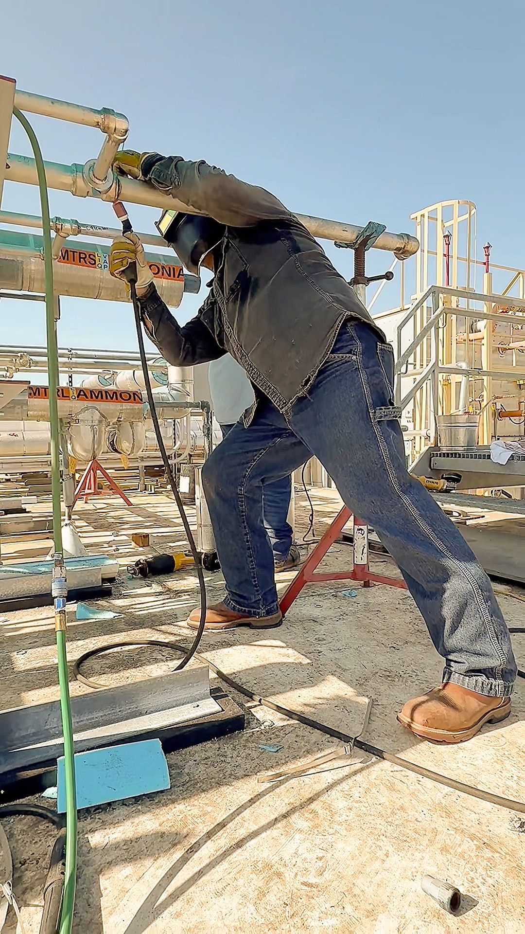 Welder working on a rooftop pipe rack