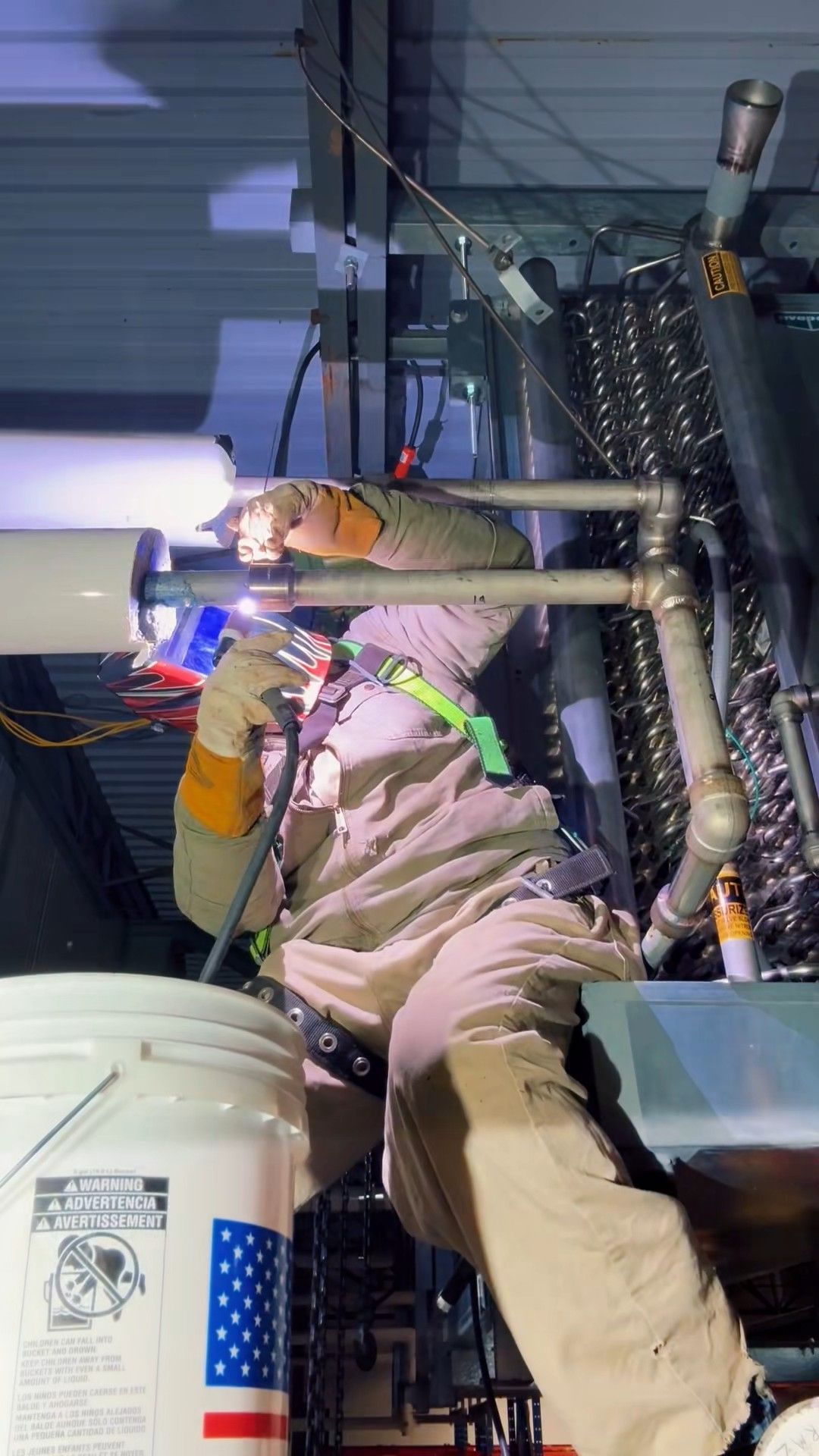 Welder working between pipes in a confined space